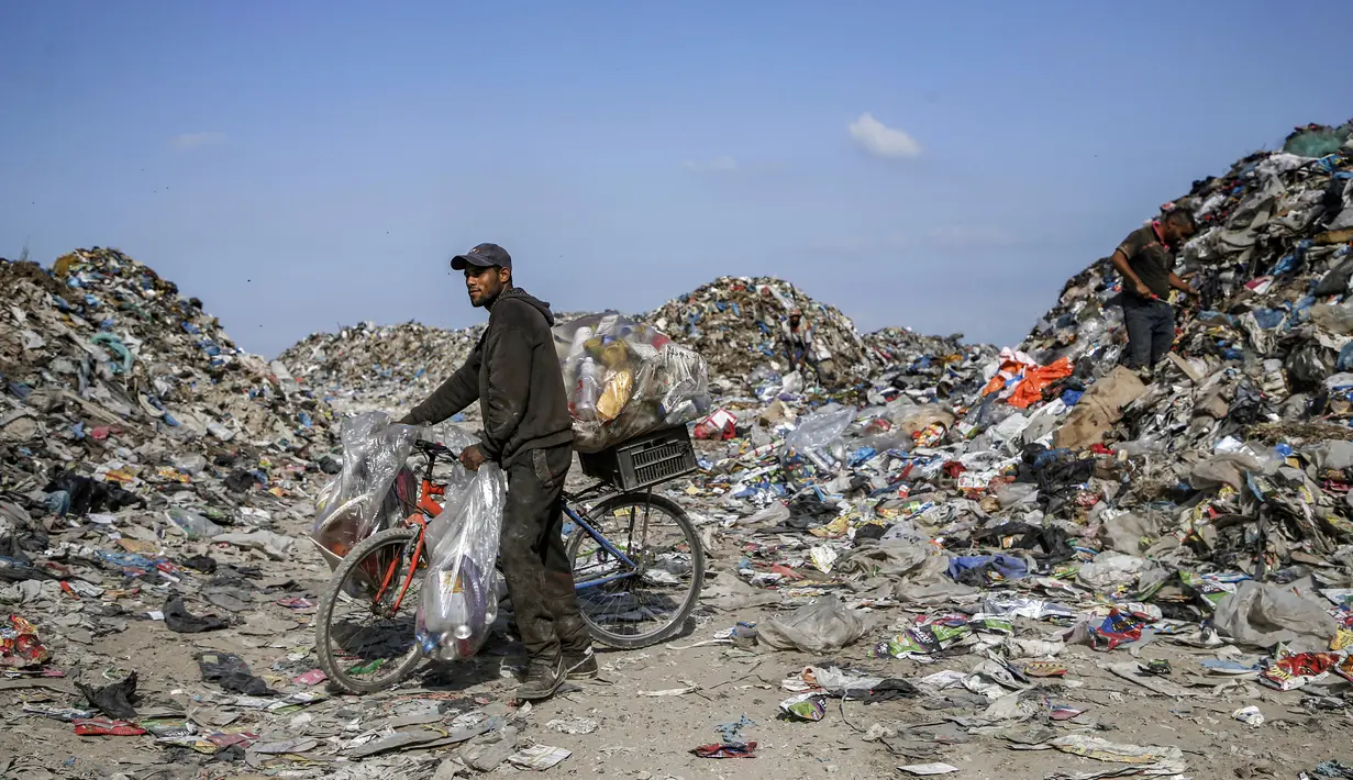Seorang pengumpul sampah Palestina mendorong sepeda yang diisi dengan kaleng-kaleng aluminium dan sampah lainnya di tempat pembuangan sampah di Kota Gaza (29/7/2019). (AFP Photo/Mohammed)
