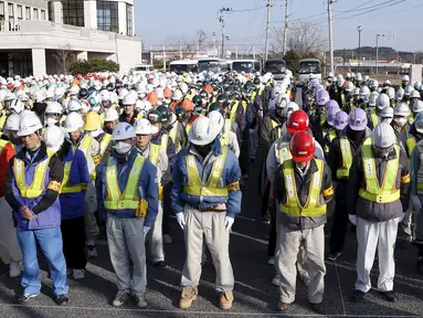 Sejumlah pekerja mengheningkan cipta untuk mengenang para korban bencana gempa dahsyat dan tsunami besar di Jepang pada 11 Maret 2011 silam, sebelum memulai pekerjaan mereka di Namie, Prefektur Fukushima, Jumat (11/3/2016). (REUTERS / Kyodo)