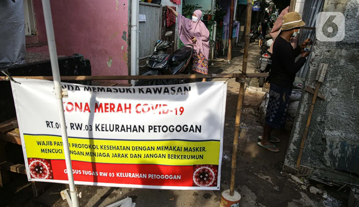 Spanduk menutup akses masuk zona merah COVID-19 di Kelurahan Petogogan RT 006 RW 003, Jakarta, Selasa (22/6/2021). Pemerintah Provinsi DKI Jakarta memperbarui data zona pengendalian virus Corona di tingkat rukun tetangga (RT) se-Ibu Kota.  (Liputan6.com/Faizal Fanani)