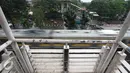 Kereta melintas di dekat JPO di kawasan Tanjung Barat, Jakarta, Jumat (11/11). Buruknya desain menyebabkan JPO tersebut tidak tersambung, sehingga warga harus membeli tiket kereta jika ingin menyeberang. (Liputan6.com/Immanuel Antonius)