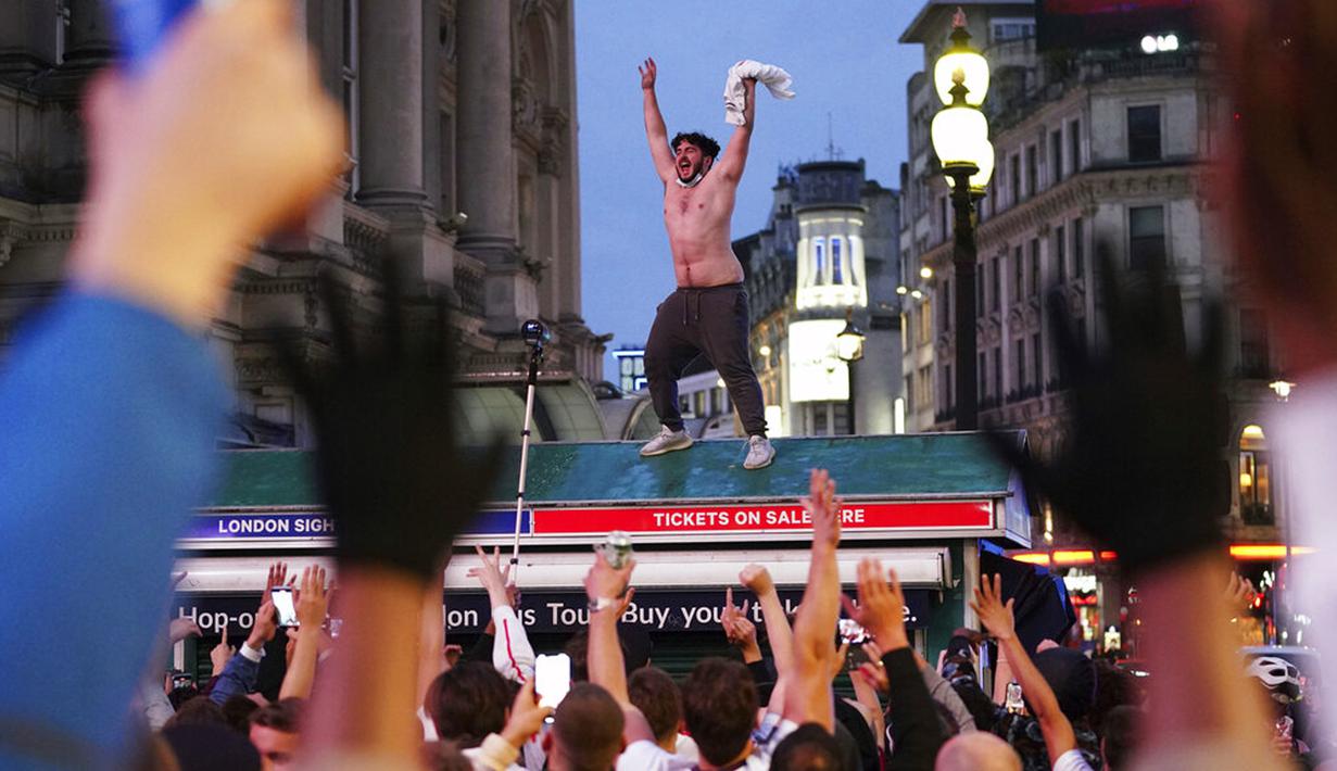 Suporter Inggris di Piccadilly Circus merayakan kemenangan Inggris atas Jerman pada pertandingan babak 16 besar Euro 2020 di London, Inggris, Selasa (29/6/2021). Inggris menang 2-0.(Yui Mok/PA via AP)