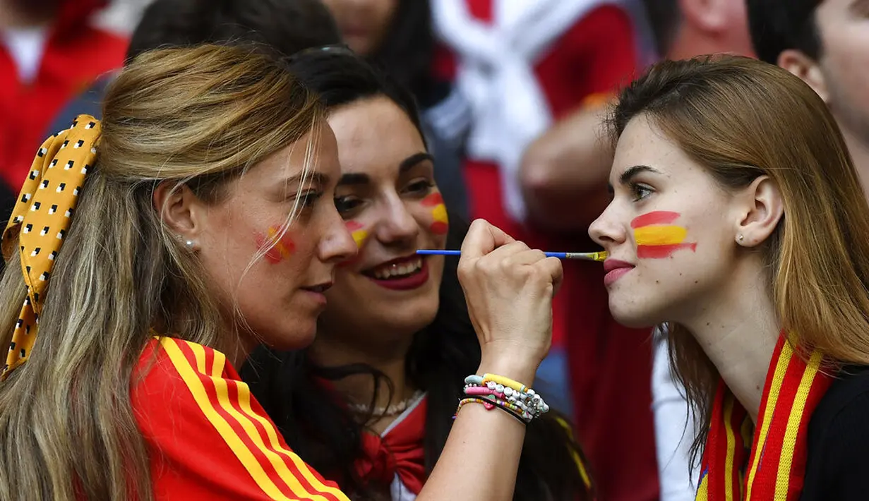 Fans wanita mengecat muka bendera Spanyol sebelum dimulainya pertandingan semifinal EURO 2020 antara Italia dan Spanyol di Stadion Wembley di London (7/7/2021). (Andy Rain/Pool via AP)