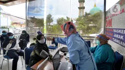 Petugas mengecek suhu tubuh tenaga kesehatan berusia lanjut sebelum menerima suntikan vaksin COVID-19 Sinovac di Puskesmas Kecamatan Jagakarsa, Jakarta, Kamis (11/2/2021). Sekitar 11 ribu nakes lansia berusia di atas 60 tahun menjadi prioritas penerima vaksin covid-19. (merdeka.com/Arie Basuki)
