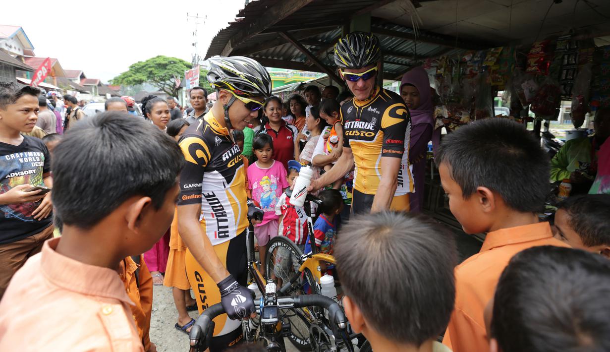 Para pebalap sepeda menjadi pusat perhatian warga saat berhenti di Barung-Barung Belantai dalam Etape 1 Tour de Singkarak antara Painan, Kabupaten Pesisir Selatan menuju Pariaman, Sumatra Barat saat, Sabtu (3/10/2015). (Bola.com/Arief Bagus)