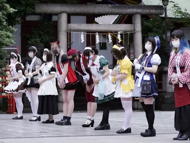 Karyawan mengenakan kostum pelayan dari beberapa kafe bertema pembantu di Akihabara berjalan setelah pertemuan doa untuk perlindungan dari COVID-19 dan untuk bisnis yang berkembang di kuil Kanda Myojin, Tokyo (25/7/2020). (AP Photo/Eugene Hoshiko)