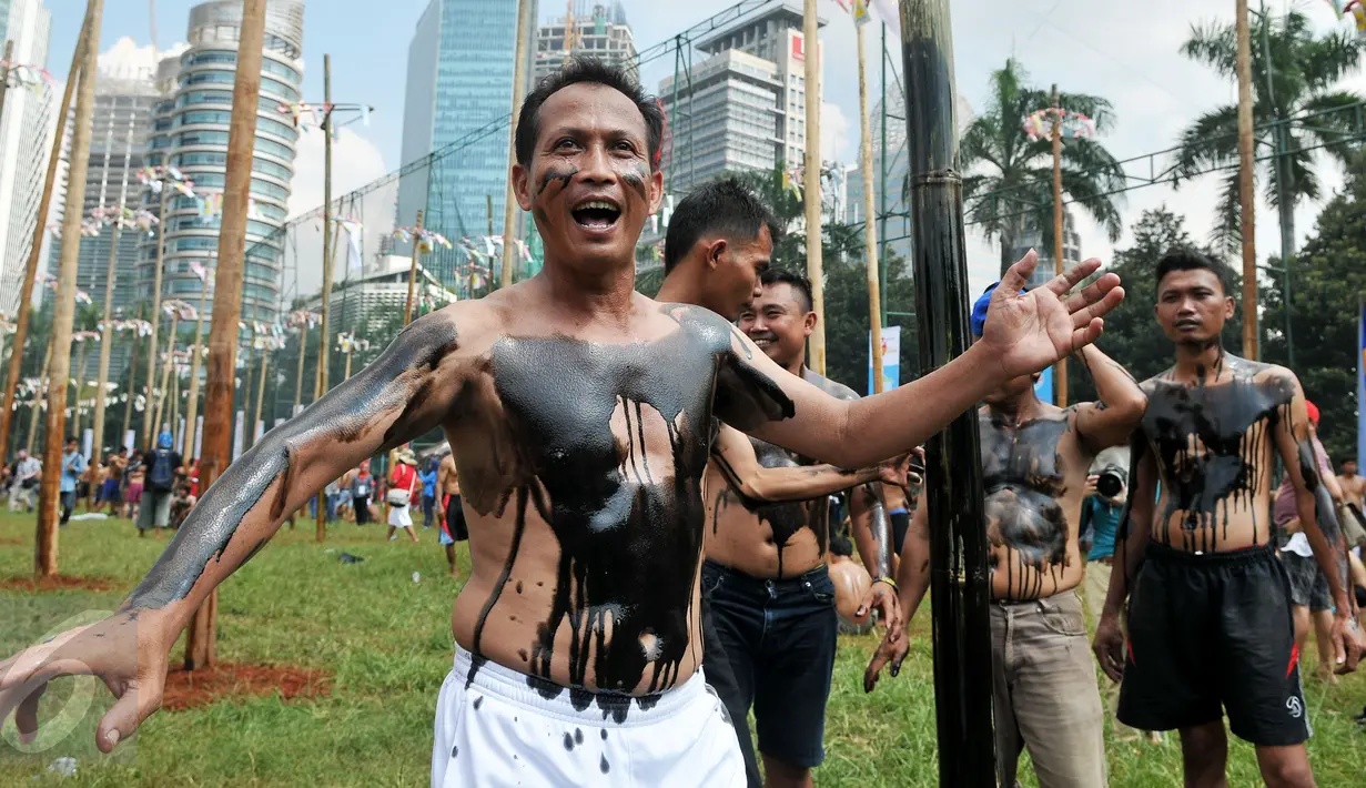 Peserta dilumuri oli bekas agar licin saat mengikuti lomba panjat pinang massal dalam rangka merayakan HUT Kemerdekaan RI ke-71 di lapangan ex Golf Driving Range Senayan, Jakarta, Rabu (17/8). (Liputan6.com/Gempur M Surya)