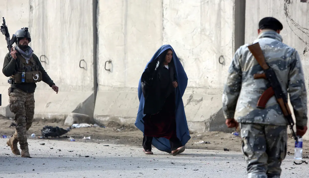 Seorang wanita Afghanistan berjalan di dekat lokasi serangan di Kabul, Afghanistan (15/1). Empat orang tewas dan 113 orang lainnya terluka akibat ledakan yang terjadi di dekat kompleks asing tersebut. (AP Photo/Rahmat Gul)