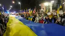 Para peserta membawa bendera raksasa Ukraina untuk memperingati satu tahun invasi Rusia ke Ukraina di depan Kedutaan Besar Rusia, Warsawa, Polandia, 24 Februari 2023. (AP Photo/Czarek Sokolowski)