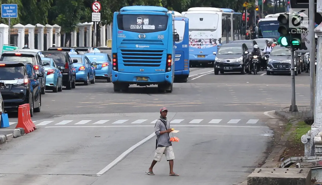 Pedagang asongan menjajakan barang dagangannya di persimpangan lampu merah di Jakarta, Jumat (22/2). Keahlian yang terbatas menyebabkan sebagian orang harus bekerja di tengah padatnya kendaraan Ibukota. (Liputan6.com/Immanuel Antonius)