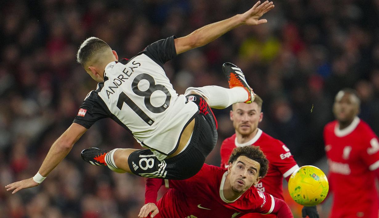 Gelandang Fulham, Andreas Pereira terpelanting saat perebutan bola dengan gelandang Liverpool, Curtis Jones pada laga leg pertama babak semifinal Carabao Cup 2023/2024 di Anfield Stadium, Liverpool, Kamis (11/1/2024) dini hari WIB. (AP Photo/Jon Super)