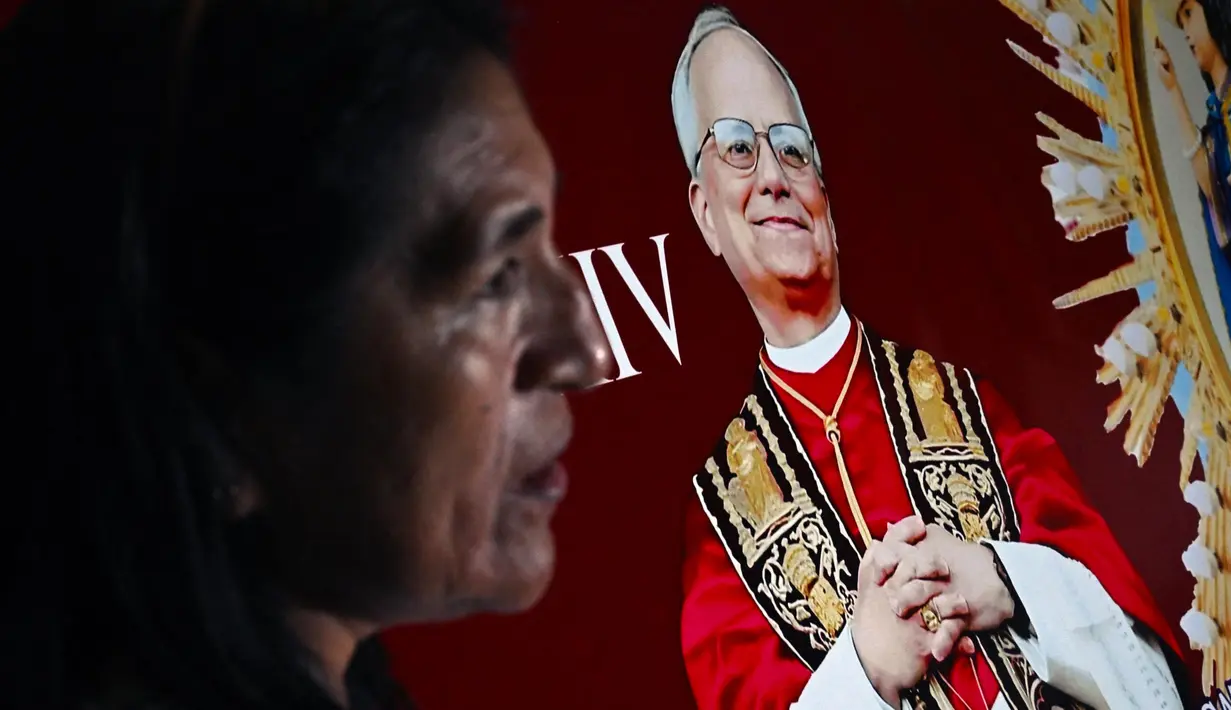 Seorang wanita berdiri di samping gambar Robert Francis Prevost, yang menjadi Paus Leo XIV pada tanggal 8 Mei 2025, di depan katedral Chiclayo di utara Lima pada hari pemilihannya sebagai paus ke-267 Gereja Katolik. (ERNESTO BENAVIDES/AFP)
