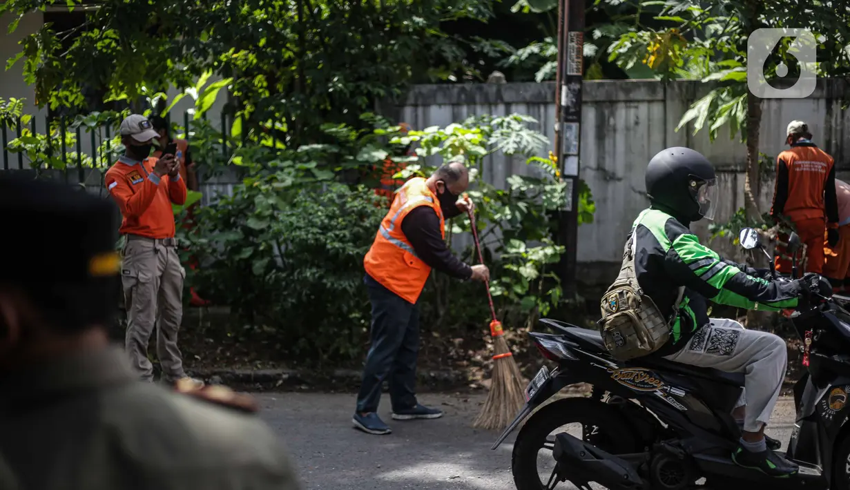 Warga menyapu jalan saat razia masker di kawasan Karang Tengah Lebak Bulus, Jakarta, Selasa (24/11/2020). Pemerintah Provinsi (Pemprov) DKI Jakarta mencatat, total denda pelanggaran protokol kesehatan mencapai Rp 4,9 miliar. (Liputan6.com/Faizal Fanani)