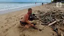 Seorang wisatawan mengumpulkan sampah yang berserakan di Pantai Kuta, Badung, Bali, Kamis (20/4/2023). (merdeka.com/Arie Basuki)