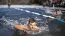 Seorang pria bertanding saat kompetisi renang musim dingin di lubang es sepanjang 25 meter di sebuah danau dekat Vilnius, Lithuania, Sabtu (6/3/2021).  Suhu air saat itu 3 derajat Celcius, sedangkan udaranya -3 derajat Celsius. (AP Photo/Mindaugas Kulbis)