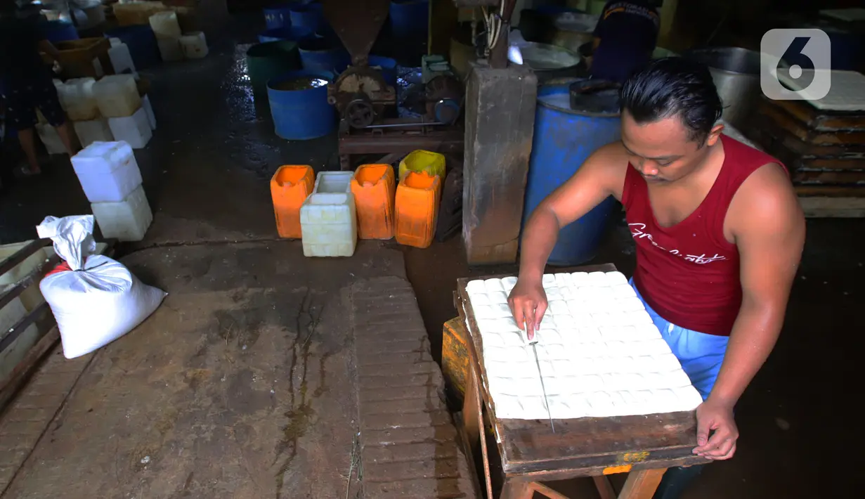 Pekerja memotong tahu dari kedelai di Jakarta, Senin (4/1/2021). Setelah melakukan mogok produksi selama 1 hingga 3 Januari 2021 akibat naiknya harga kacang kedelei impor, kini para perajin tahu mulai kembali beroperasi. (Liputan6.com/Angga Yuniar)