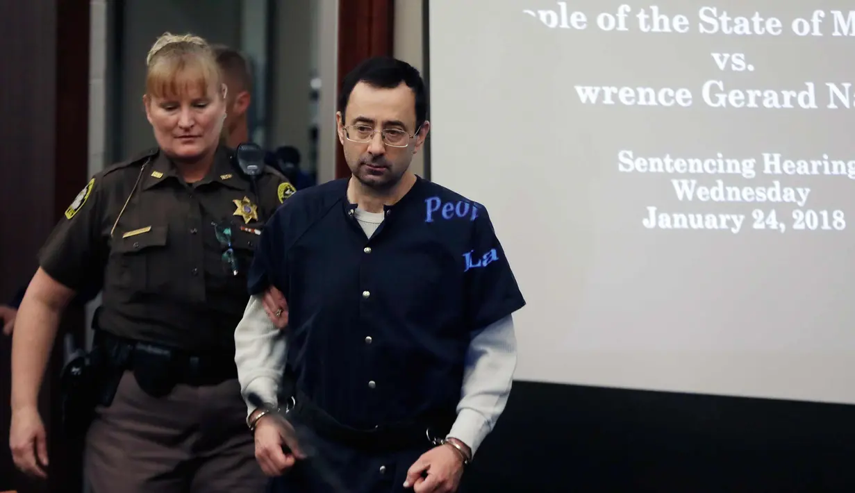 Dokter Larry Nassar didampingi petugas bersiap menjalani sidang vonis hukuman di Lansing, Mich (24/1). Ratusan tuntutan diarahkan ke Nassar terkait kasus pelecehan seks, dengan dalih perawatan medis. (AP Foto / Carlos Osorio)