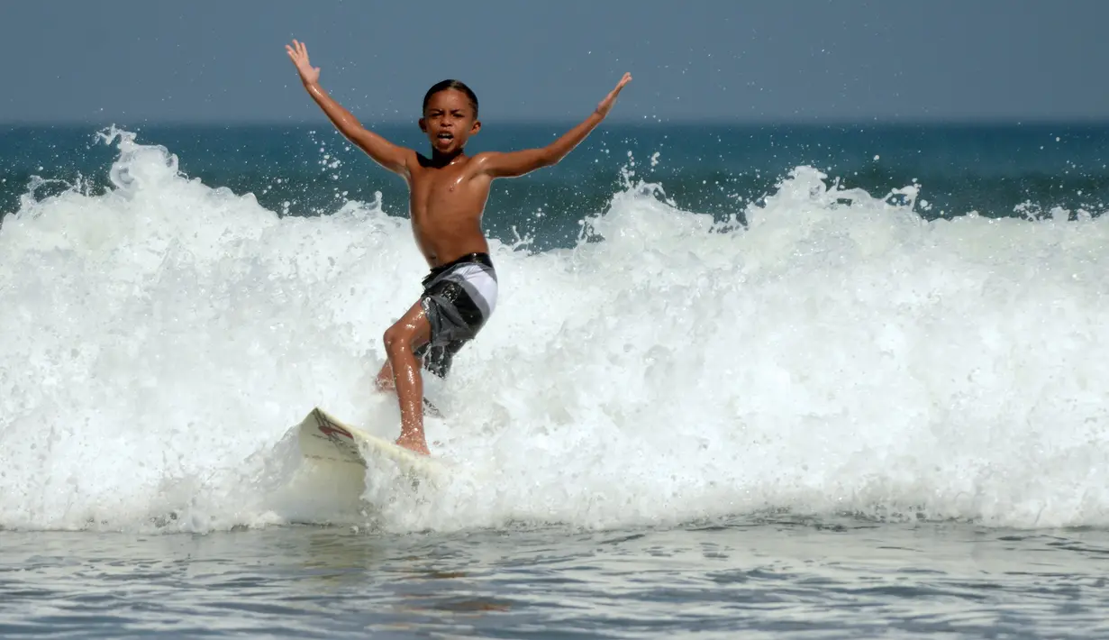 Natan Bontje selama latihan di pantai Kuta dekat Denpasar di pulau resor Indonesia Bali (6/5). Natan berusia sembilan tahun merupakan peserta termuda yang mengikuti kompetisi Asian Surfing Tour 2018 yang telah berakhir. (AFP Photo/Sonny Tumbelaka)