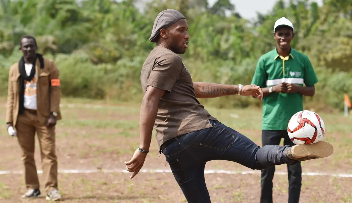 Mantan penyerang Chelsea, Didier Drogba berusaha mengontrol bola saat bermain dengan murid-murid saat peresmian sekolah di Pokou-Kouamekro, dekat Gagnoa, Pantai Gading tengah barat (17/1). (AFP Photo/Sia Kambou)