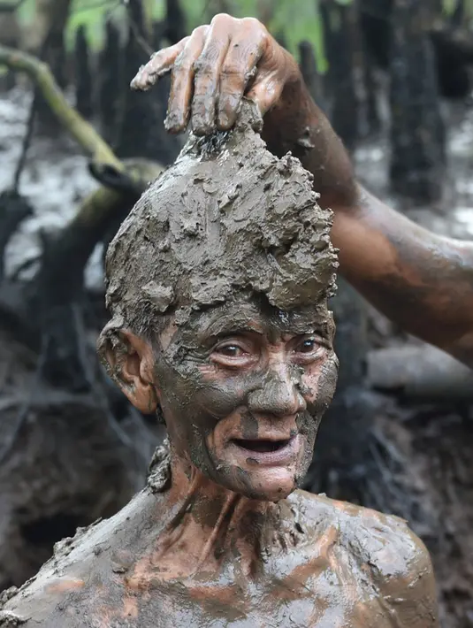 Seorang pria mengambil bagian dalam tradisi mandi lumpur yang dikenal sebagai Mebuug-buugan di Desa Kedonganan, Bali, 4 Maret 2022. Mebuug-buugan diadakan sehari setelah Nyepi yang bertujuan untuk menetralkan sifat buruk. (SONY TUMBELAKA/AFP)