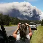 Seorang wanita berada di mobilnya mengambil gambar kepulan abu vulkanik dari gunung berapi Kilauea di Big Island Hawaii (15/5). (Mario Tama/Getty Images/AFP)