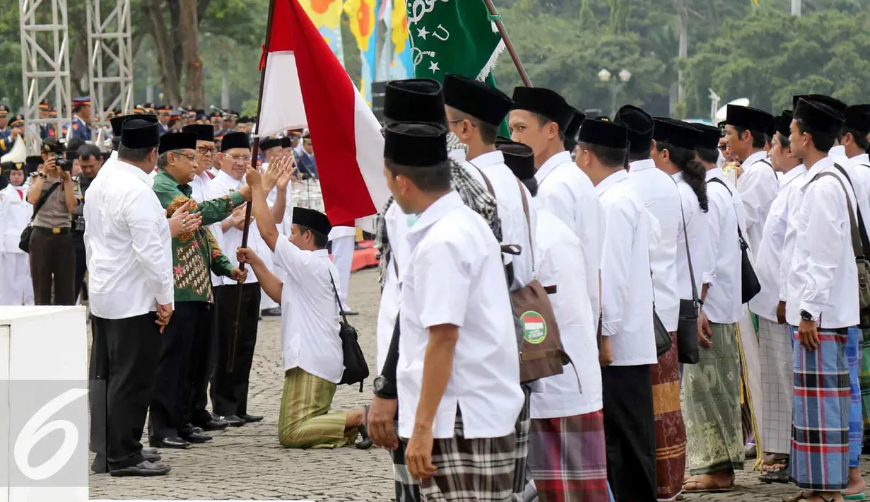 Ketua Umum PBNU Said Aqil Siradj memberikan bendera merah putih kepada santri dalam Upacara Hari Santri Nasional di silang Monas, Jakarta, Sabtu (22/10). (Liputan6.com/Fery Pradolo)