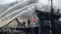 Para pekerja mencoba membantu memadamkan api di kapal nelayan di Pelabuhan Benoa, Denpasar, Bali, Senin (9/7). Hingga kini pemilik kapal masih belum bisa dimintai keterangan. (SONNY TUMBELAKA/AFP)