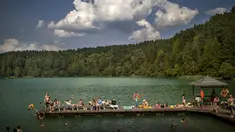 Orang-orang menikmati cuaca hangat di tepi danau dekat Vilnius, Lituania, Kamis, 17 Agustus 2023.(AP Photo/Mindaugas Kulbis)