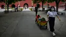 Seorang perempuan menarik gerobak portabel dengan seorang anak mendorong ke belakang ketika bersiap untuk mengunjungi Kota Terlarang di Beijing, China, Selasa (7/6/2022). Pemerintah melonggarkan beberapa pembatasan Covid-19 dengan sebagian besar museum gedung bioskop, dan pusat kebugaran diizinkan beroperasi hingga 75 persen dari kapasitas. (WANG Zhao / AFP)
