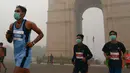 Peserta yang mengikuti lomba New Delhi 10K berlari di depan India Gate menggunakan masker di New Delhi, India (31/10). Partikel ini dapat menyebabkan batuk, bersin hingga sesak napas. (AFP/Dominique Faget)