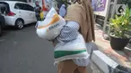 Warga berjalan dengan membawa beras kemasan 10 kilogram di Kelurahan Pela Mampang, Jakarta, Jumat (3/5/2024). (merdeka.com/Imam Buhori)