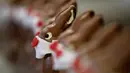 Pekerja menyiapkan cokelat paskah berbentuk kelinci yang mengenakan masker di toko roti Baeckerei Bohnenblust di Bern, Swiss, Jumat (27/3/2020). Cokelat paskah yang dibuat di tengah pandemi virus corona yang sedang merebak di seluruh dunia ini dijual sekitar RP 143 ribu. (STEFAN WERMUTH/AFP)