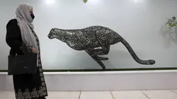Pengunjung melewati patung cheetah dari mesin cuci besi tua di area indoor Shahreza Metal Zoo di pusat kota Shahreza sekitar 425 kilometer selatan ibu kota Teheran, Iran pada 13 Oktober 2021. Kebun binatang tersebut menampung 30 patung hewan dengan berbagai ukuran. (AP Photo/Vahid Salemi)