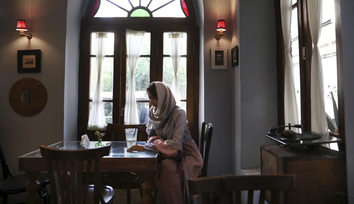Seorang wanita menghabiskan sore di sebuah kafe di pusat kota Teheran, Iran (10/8/2019). Teheran adalah kota yang sarat dengan kehidupan yang terletak di kaki pegunungan Alborz dengan jaringan jalan tol yang tak tertandingi di Asia Barat. (AP Photo/Vahid Salemi)
