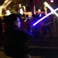Dua orang pria saling beradu lightsaber (pedang sinar) saat mengikuti Glow Battle Tour di Grand Park, Los Angeles (15/12). Para penggemar ini berkumpul dengan membawa pedang sinar yang beraneka warna. (Photo by Chris Pizzello/Invision/AP)