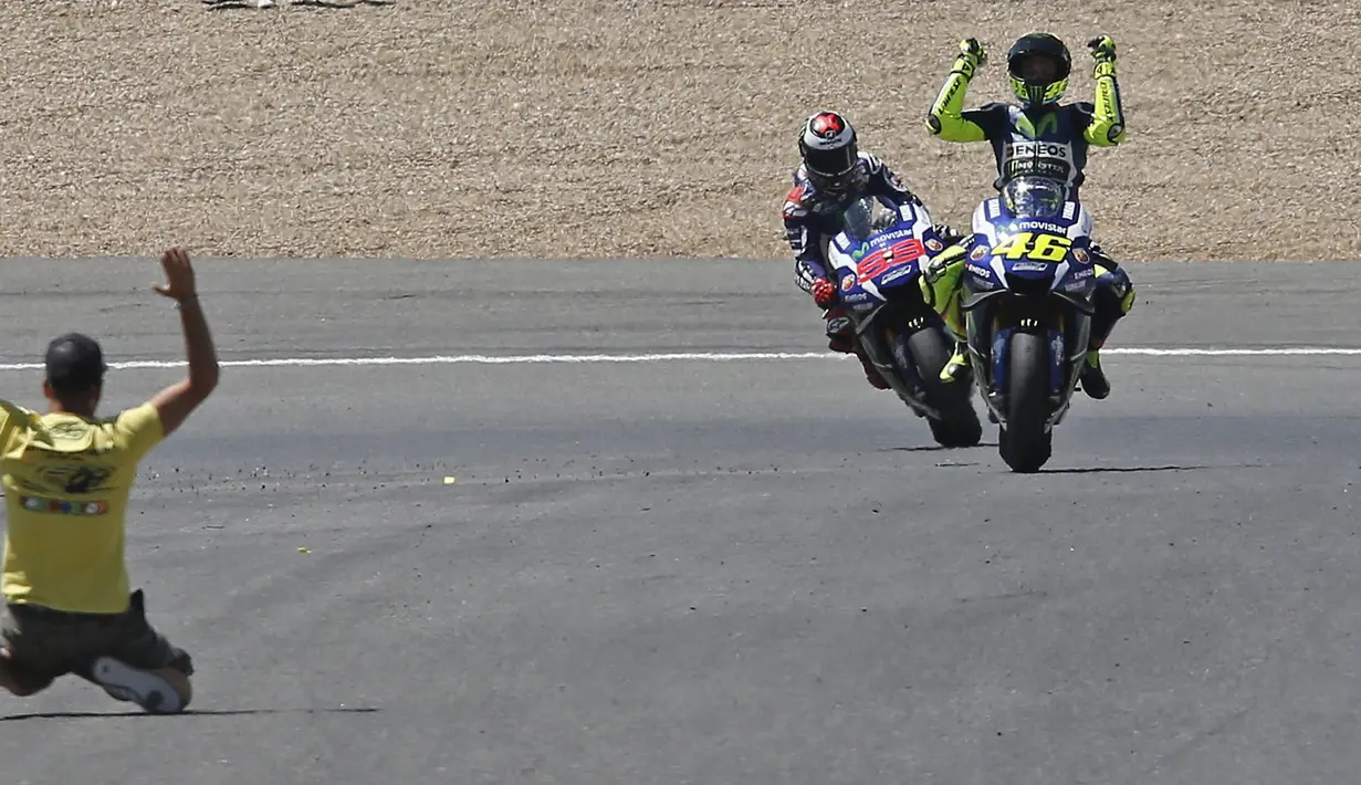 Seorang penonton memasuki lintasan setelah Valentino Rossi finis pertama diikuti Jorge Lorenzo dan Marc Marquez. (EPA/Jose Manuel Vidal)