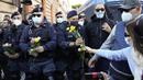 Demonstran membawa bunga untuk petugas polisi selama aksi protes di Circus Maximus Roma, Jumat (15/10/2021). Protes tersebut karena aturan yang mengharuskan seluruh pekerja di Italia menunjukkan kartu kesehatan covid-19 untuk memasuki tempat kerja mereka. (AP Photo/Gregorio Borgia)