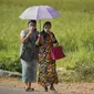 Wanita etnis Khasi dengan pakaian tradisional mengenakan masker berjalan di desa Umwang, di sepanjang perbatasan negara bagian Assam-Meghalaya, India, Rabu (27/10/2021). Lebih dari 60 persen dari 1,3 miliar warga India bertani. (AP Photo/Anupam Nath)