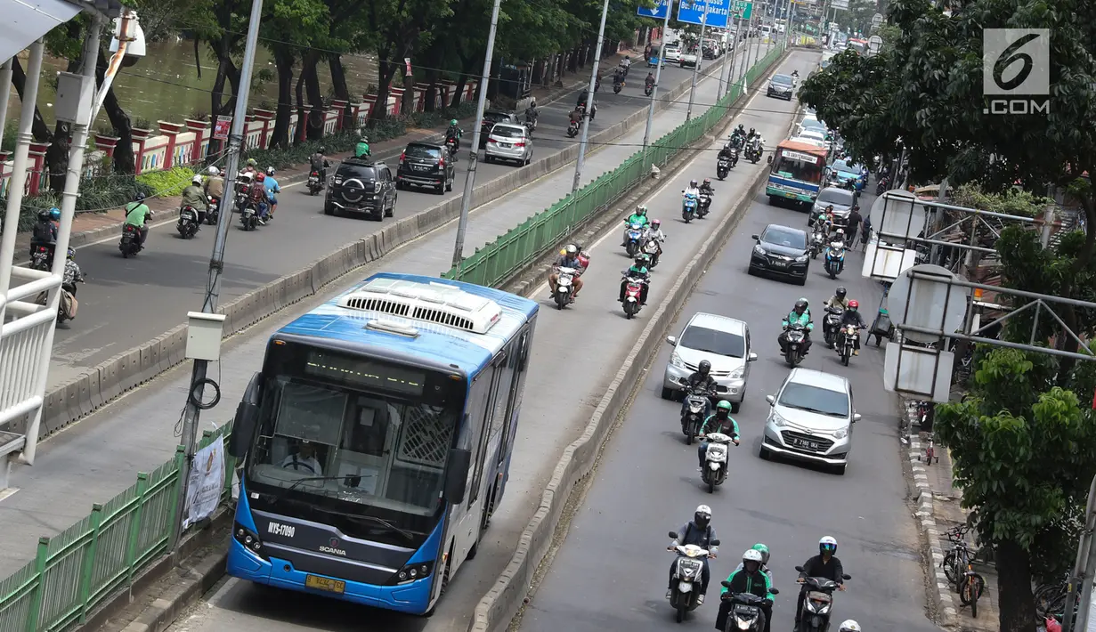 Pengendara motor melaju di belakang bus Transjakarta di kawasan Pasar Rumput, Jakarta, Rabu (20/2). Sekitar 510 CCTV akan dipasang di 225 halte Transjakarta di Ibu Kota untuk menerapkan tilang online atau E-Tilang. (Liputan6.com/Immanuel Antonius)