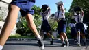 Anak-anak sekolah menggunakan tas mereka untuk melindungi diri saat latihan gempa dan tsunami di Tanjung Benoa, Kabupaten Badung, Bali, 24 Mei 2022. (SONY TUMBELAKA/AFP)