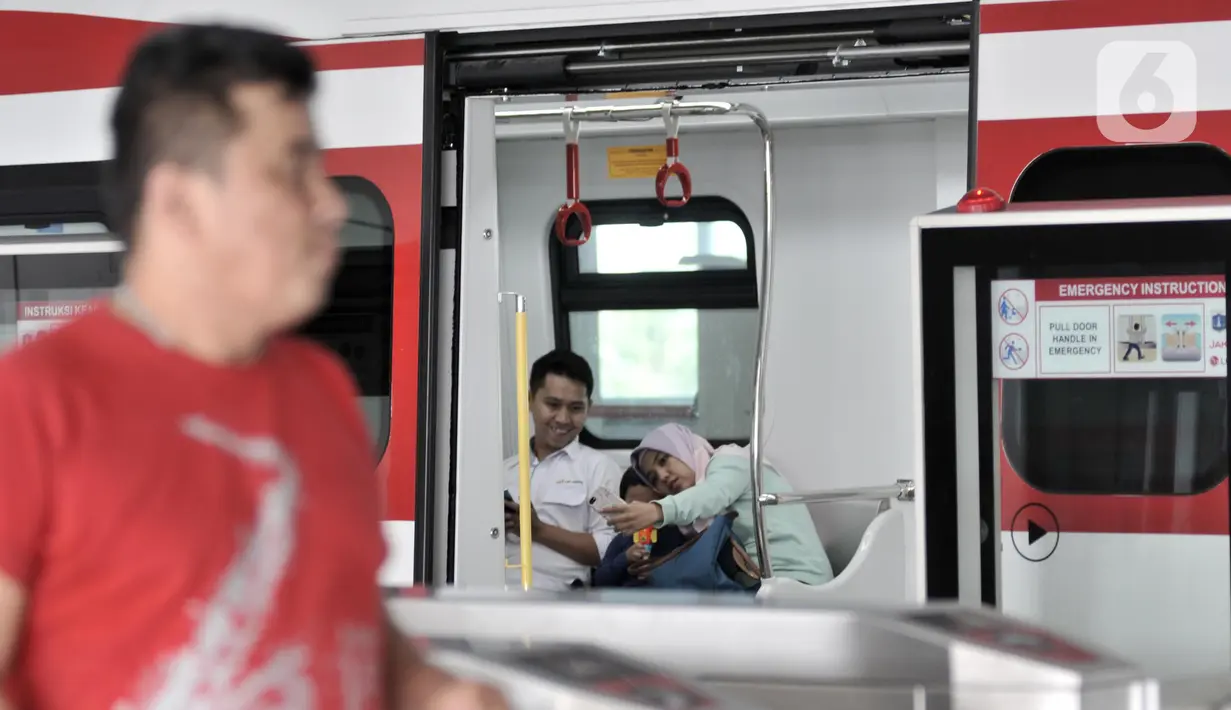 Penumpang berswafoto di dalam gerbong kereta LRT di Stasiun Velodrome, Jakarta, Minggu (1/12/2019). Kereta LRT Jakarta rute Velodrome-Kelapa Gading beroperasi secara komersial mulai hari ini (1/12) dengan tarif Rp5.000 flat untuk sekali perjalanan. (merdeka.com/Iqbal S. Nugroho)
