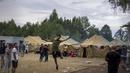 Seorang migran melompat ketika yang lain berjalan di dalam kamp pengungsi yang baru dibangun di tempat latihan militer Rudninkai, sekitar 38 km (23,6 mil) selatan dari Vilnius, Lithuania, Rabu (4/8/2021). (AP Photo/Mindaugas Kulbis)