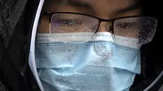 Rintik hujan mengumpul di kacamata dan masker wajah seorang pria saat ia menunggu di persimpangan pada hari hujan selama jam sibuk pagi hari di Beijing, Rabu (29/6/2022). China pada hari Selasa memutuskan untuk memangkas setengah waktu karantina bagi pelancong yang masuk ke Negara Tirai Bambu itu. (AP Photo/Mark Schiefelbein)