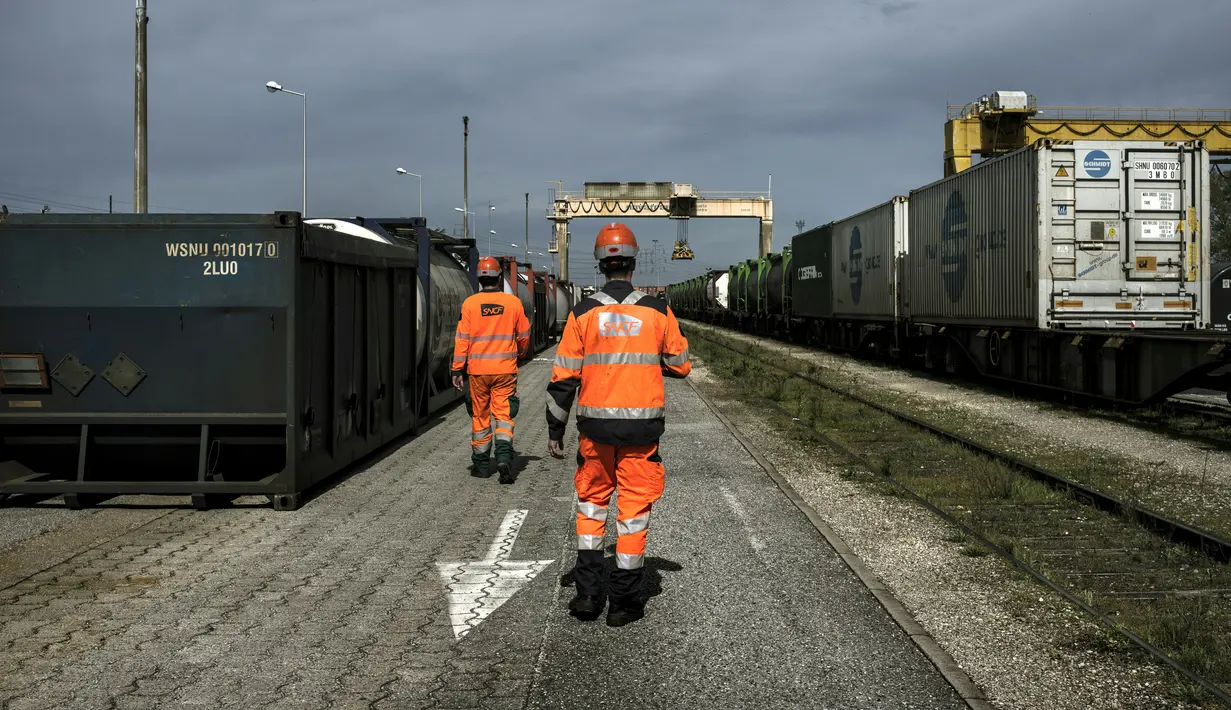 Sejumlah pekerja berjalan di stasiun kereta api barang di Saint-Priest, Lyon Prancis, (21/4). Untuk pertama kali, kereta barang yang mengangkut 41 kontainer dari China tiba di Prancis. (AFP PHOTO/JEFF PACHOUD)