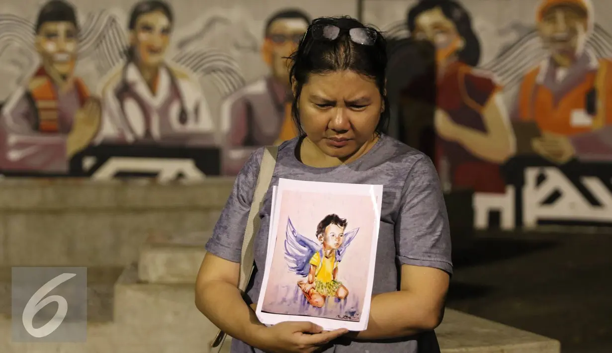Seorang wanita membawa lukisan korban bom Samarinda Intan Olivia Marbun saat doa bersama di depan Istana Negara, Jakarta, Selasa (15/11). Doa bersama digelar sebagai bentuk dukacita akibat aksi pelemparan bom di Samarinda.(Liputan6.com/Immanuel Antonius)