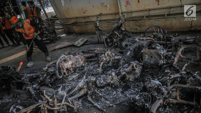 Petugas mengumpulkan bangkai sepeda motor yang dibakar massa aksi di bawah jembatan layang Slipi, Jakarta, Kamis (26/9/2019). Aksi menolak revisi UU KPK, revisi UU KUHP dan sejumlah revisi UU lainnya berjalan anarkis di sekitar Gedung DPR pada Rabu 25 September 2019. (Liputan6.com/Faizal Fanani)