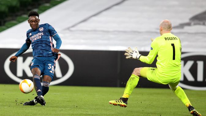 Striker Arsenal, Folarin Balogun (kiri) mencetak gol ke gawang Dundalk selama pertandingan Grup B Liga Europa 2020/2021 di Stadion Aviva, Jumat (11/12/2020) dini hari WIB. Arsenal menang 4-2 saat bertandang di markas wakil Irlandia, Dundalk. (Paul Faith / AFP)