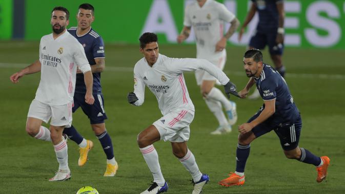 Bek Real Madrid, Raphael Varane (tengah) berusaha mengejar striker Celta Vigo, Nolito (kanan) pada pertandingan lanjutan La Liga Spanyol di stadion Alfredo Di Stefano, Minggu (3/1/2021). Sementara bagi Celta Vigo, hasil ini tetap menempatkan mereka di posisi kedelapan. (AP Photo/Manu Fernandez)