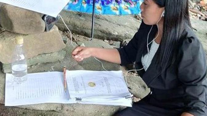 Seorang mahasiswi asal Manado mencari sinyal hingga ke tepi pantai agar bisa melaksanakan ujian skripsi dengan lancar.