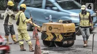 Pekerja dengan alat berat melakukan perbaikan jalan berlubang di Jalan DI Panjaitan, Cawang, Jakarta, Senin (25/1/2021). Perbaikan jalan rusak dan berlubang akibat sering tergenang banjir di kawasan tersebut untuk mengantisipasi terjadinya kecelakaan pengendara. (merdeka.com/Iqbal S Nugroho)