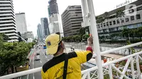 Kesibukan pekerja saat melakukan pengecatan ulang tiang Jembatan Penyeberangan Orang (JPO) di kawasan Thamrin, Jakarta, Kamis (28/1/2021). Pengecatan ulang tersebut dilakukan untuk merawat dan memelihara keberadaan fasilitas umum tersebut. (Liputan6.com/Faizal Fanani)